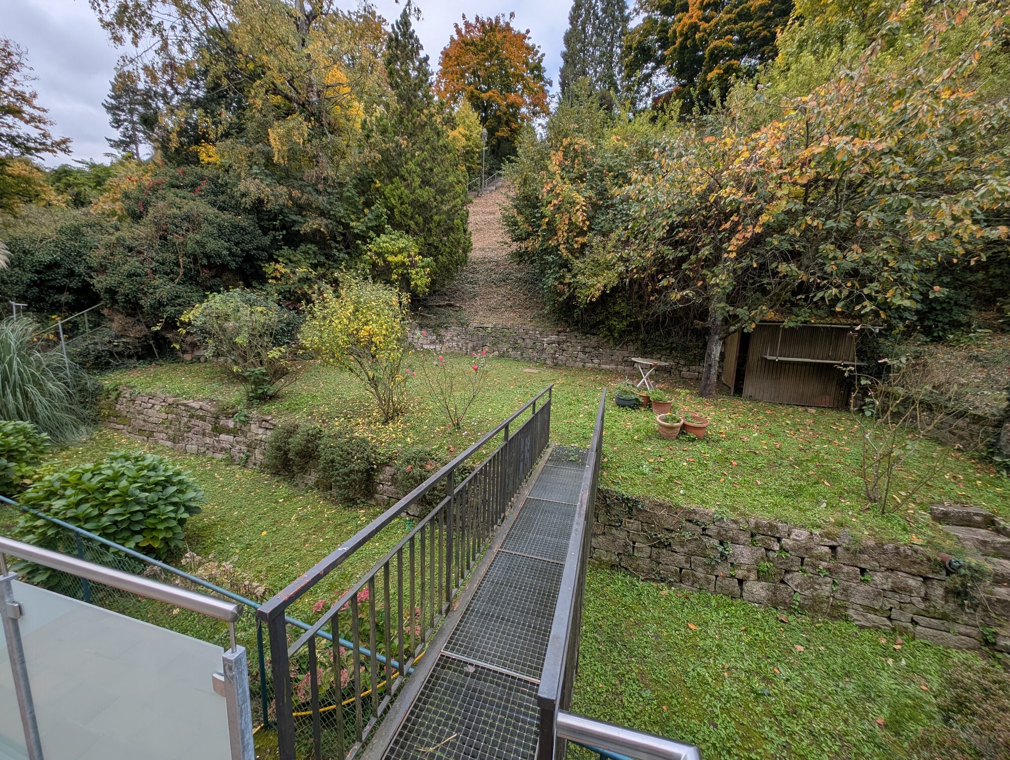 Blick über den Brückensteg in den eigenen Garten der Wohnung, terrassiert und mit altem Baumbestand